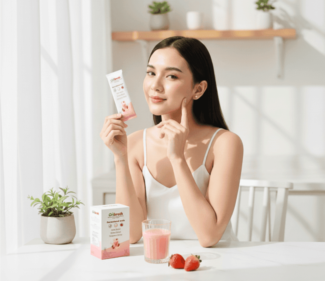 Wanita sedang tersenyum dan membawa sachet Oribroth wajah bebas Jerawat Hormonal karena rutin minum Oribroth Acne Hormonal Drink